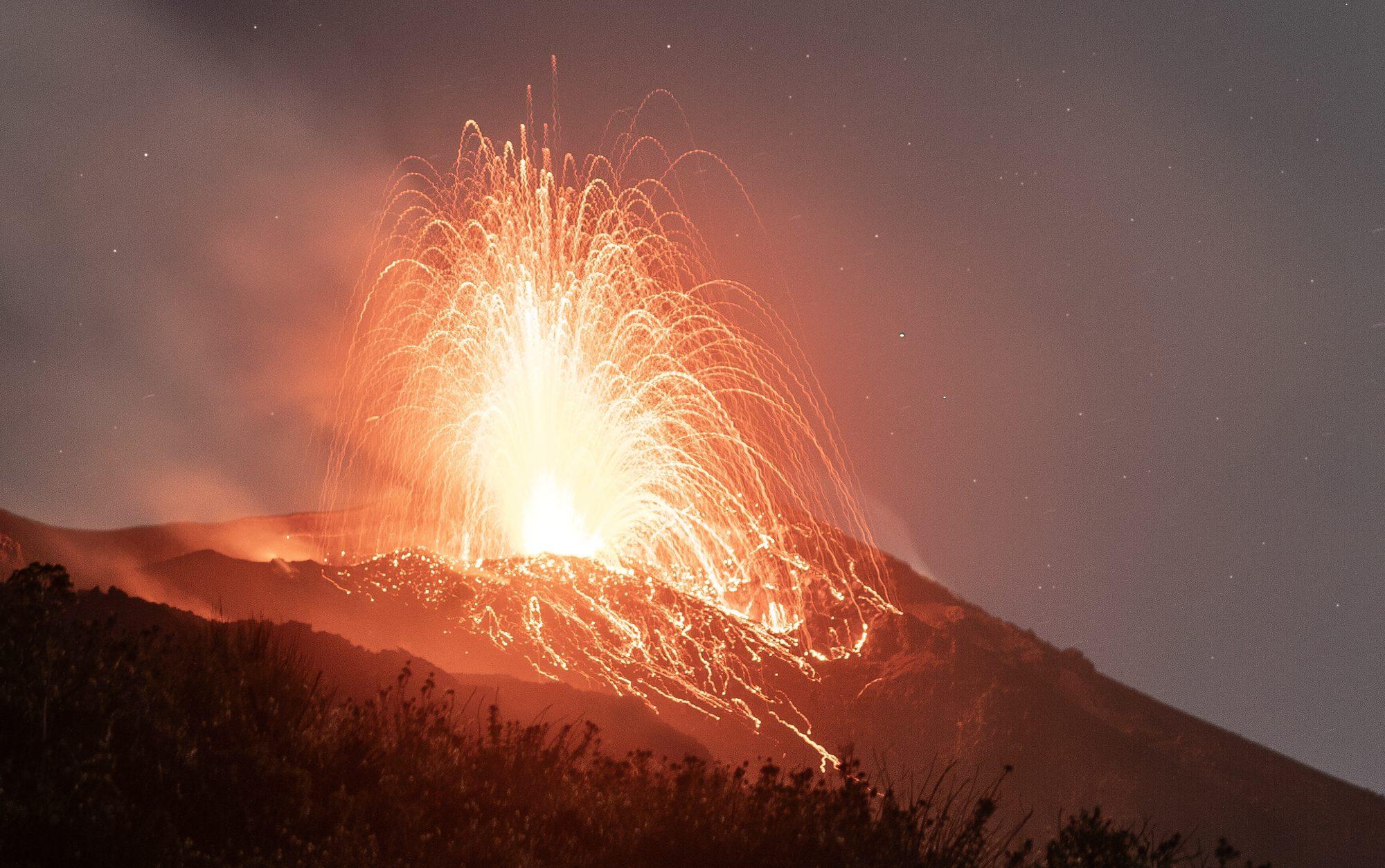 A volcanic eruption throwing lava into the night sky