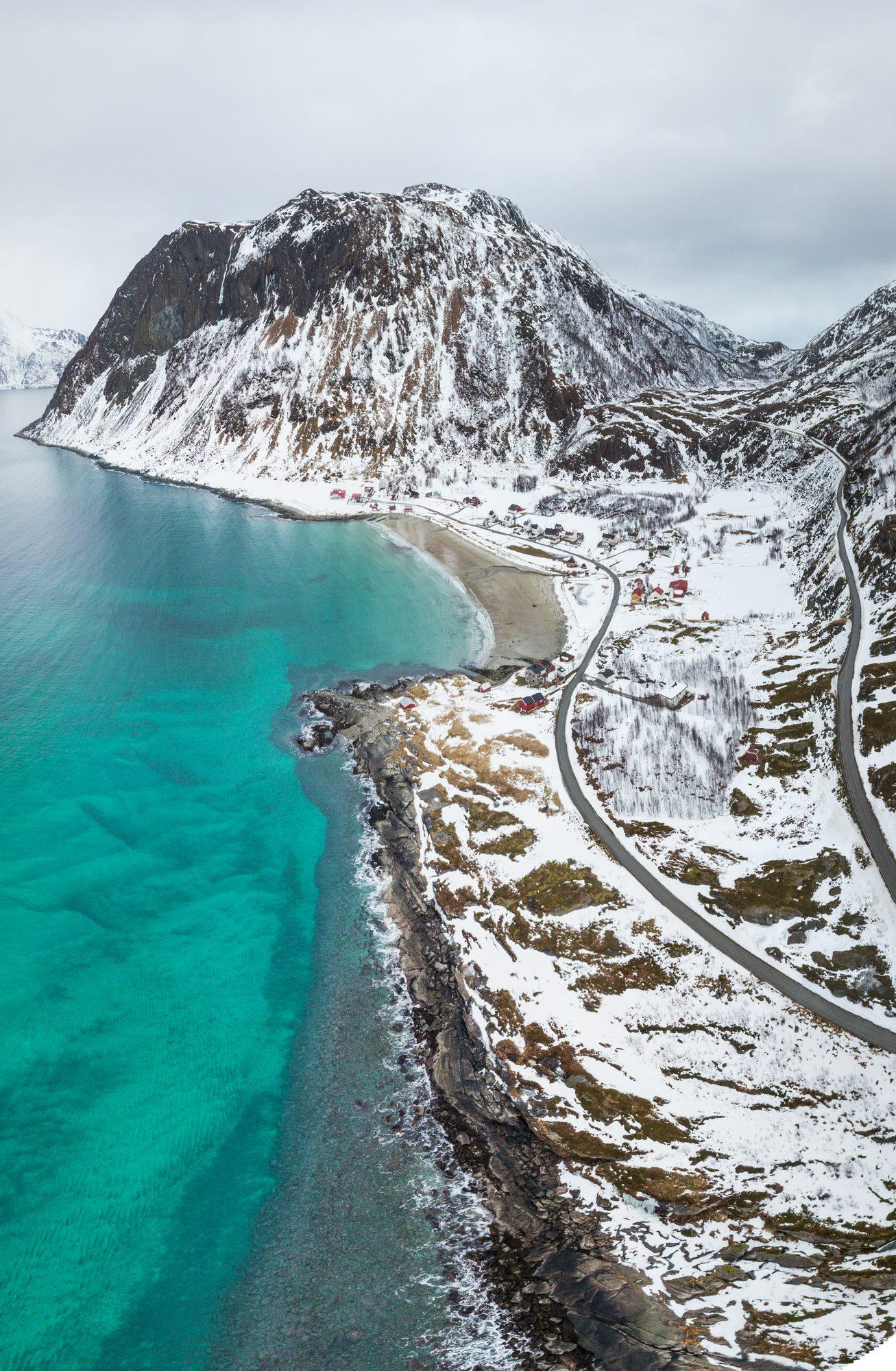 Turquoise shallows meeting a snow-dusted mountain shore
