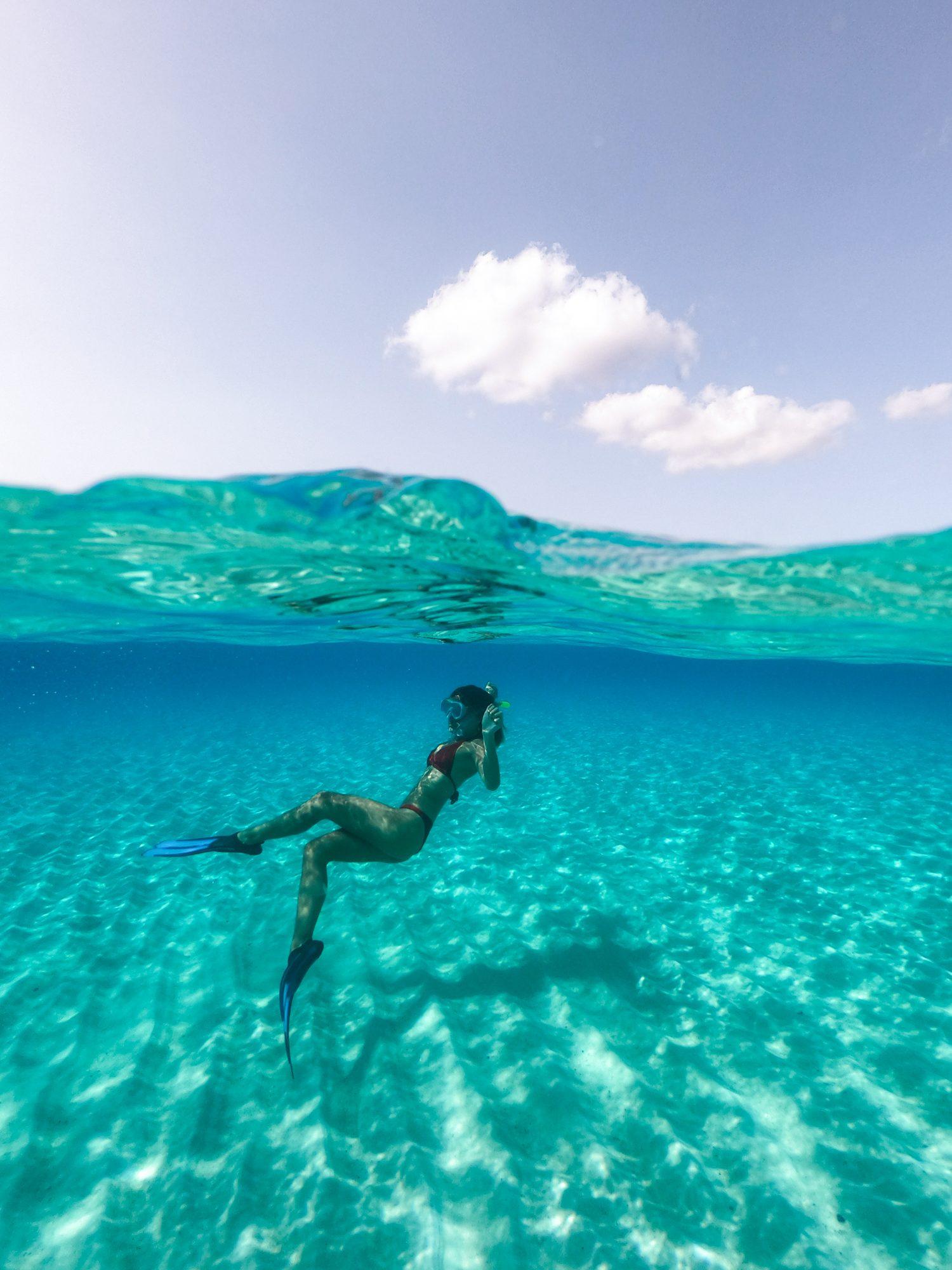Split-level shot of a freediver in clear turquoise water