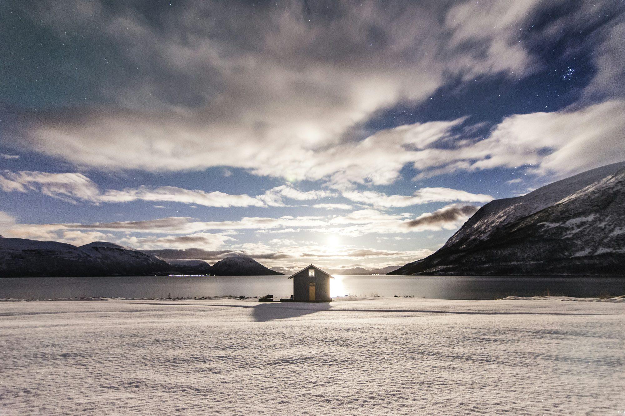 A lone cabin on a frozen loch under dramatic skies