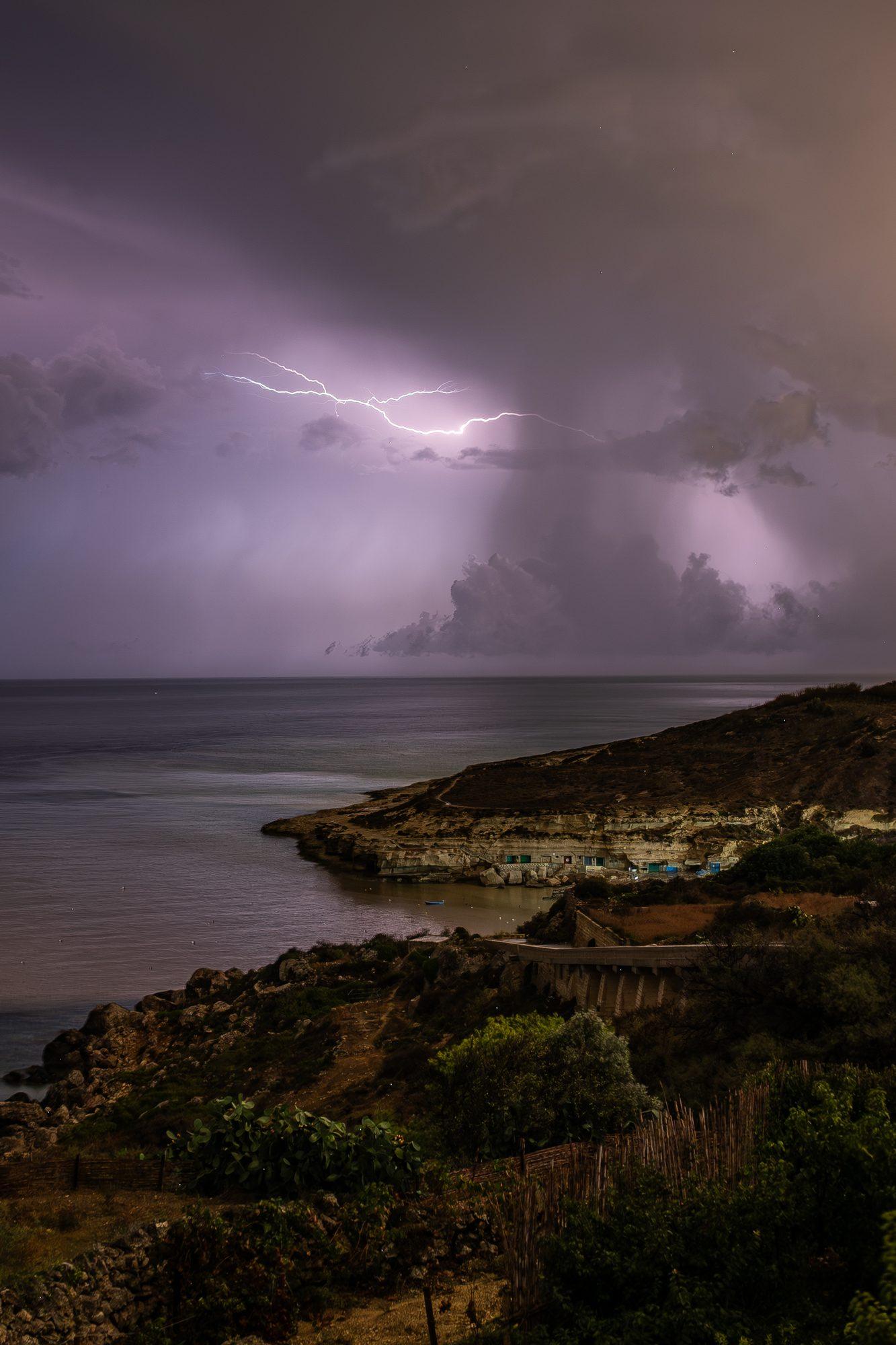 Lightning striking over a rugged coastline