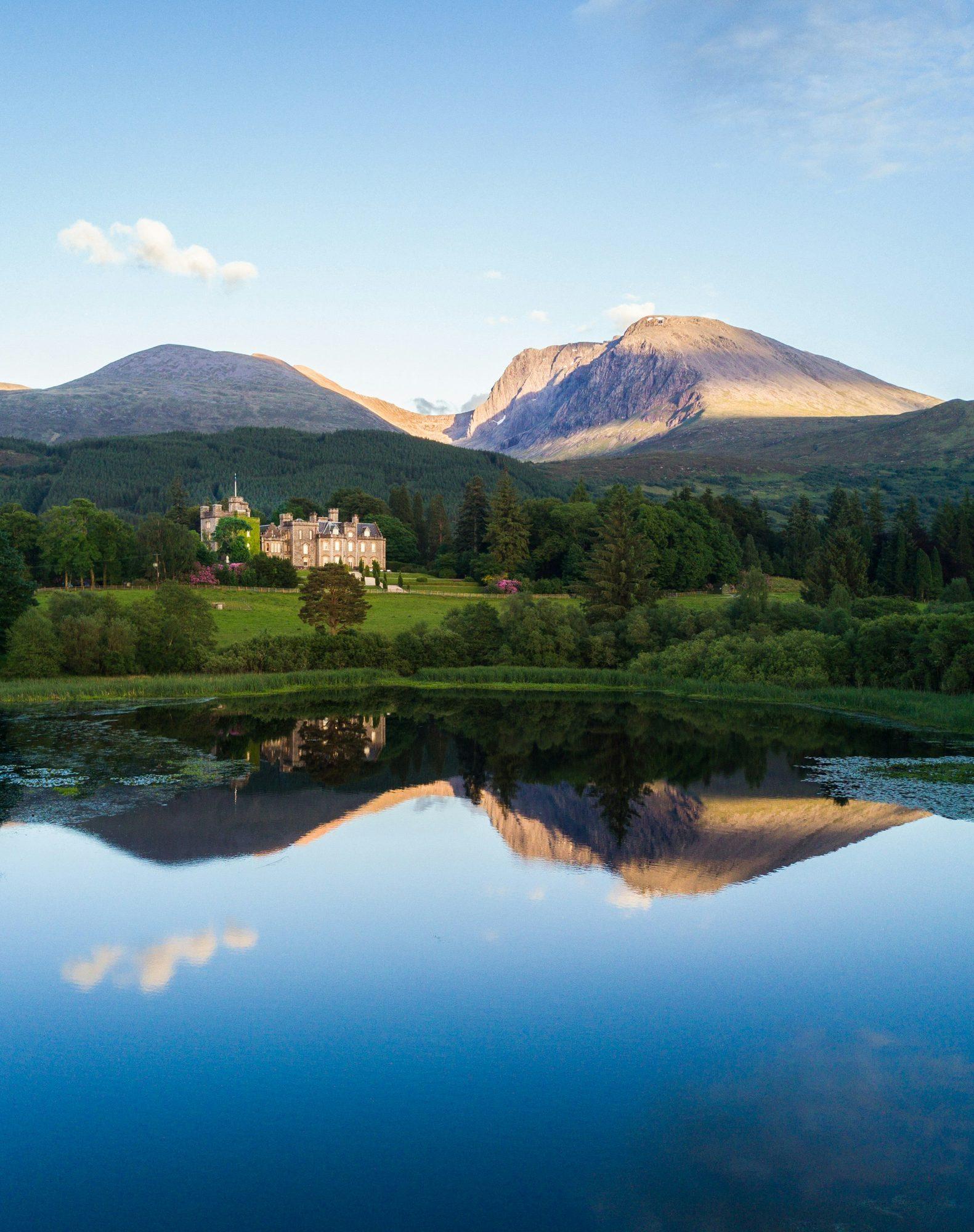 A castle reflected in still water below mountains